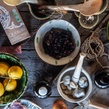 Tabletop scene with lemons, olives, and other ingredients on a wooden surface.