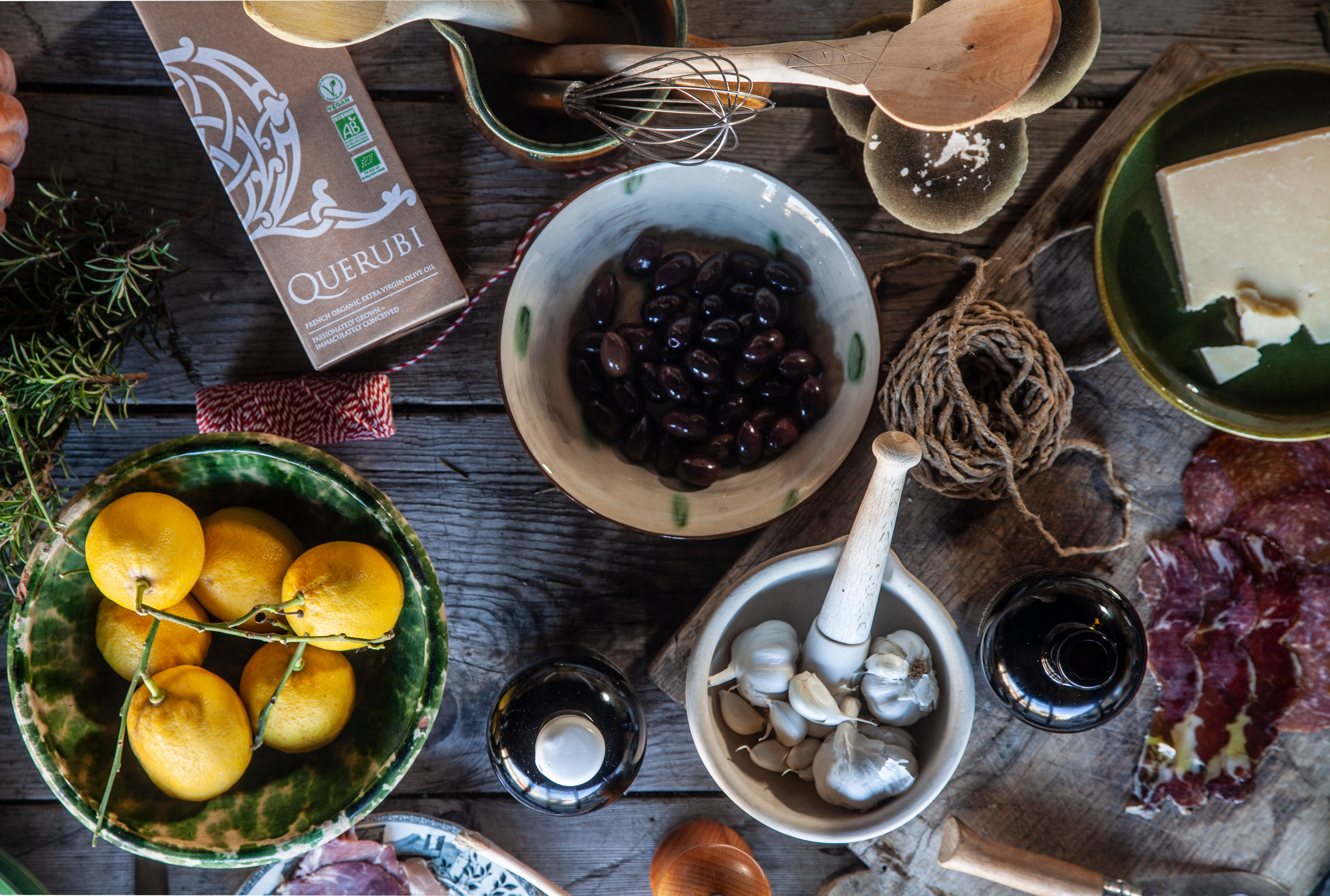 Tabletop scene with lemons, olives, and other ingredients on a wooden surface.