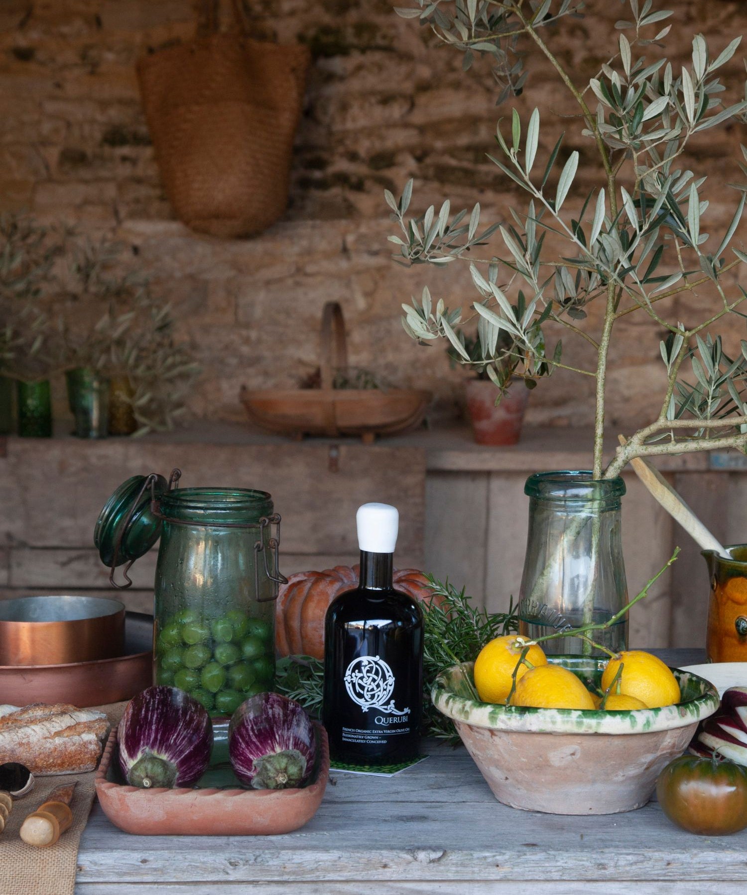 Querubi organic extra virgin olive oil bottles styled with olive branch, artichokes and lemons